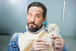 Man looking at his slippery dentures suspiciously 